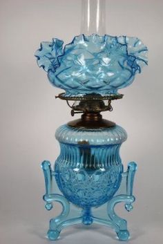 a blue glass vase sitting on top of a table next to a candle holder with a light