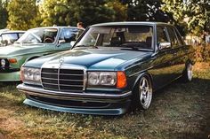 two mercedes benzs are parked next to each other on the grass in front of trees