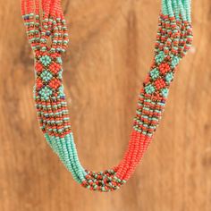 This awe-inspiring beaded necklace is a work of art crafted with an exquisite blend of orange, aqua and bronze glass beads that form multiple strands connected by woven patches featuring lovely floral motifs. Handmade by Guatemala's Angelina Roquel with love and care, this multi-strand necklace is the perfect accessory to bring glamor to your wardrobe. Bohemian Orange Hand-strung Necklace, Orange Bohemian Hand-strung Beaded Necklace, Unique Multi-strand Jewelry With Spacer Beads, Artisan Multi-strand Jewelry With Spacer Beads, Unique Orange Beaded Necklace, Traditional Coral Beaded Necklaces With Colorful Beads, Unique Orange Beaded Necklace With Colorful Beads, Unique Handmade Coral Beaded Necklace, Handmade Artisan Coral Beaded Necklaces