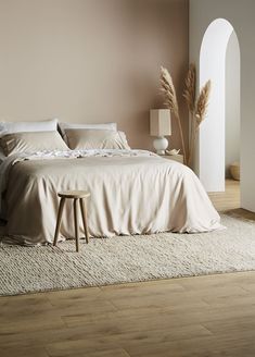 a large bed sitting on top of a wooden floor next to a tall white wall