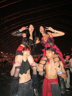 three women in costumes posing for a photo at an outdoor event with other people around them