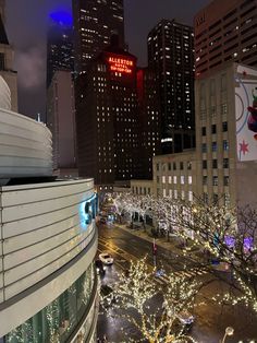 the city is lit up at night with christmas lights on trees and buildings in the background