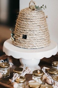 a white cake on top of a table covered in buttons and twine rope with flowers