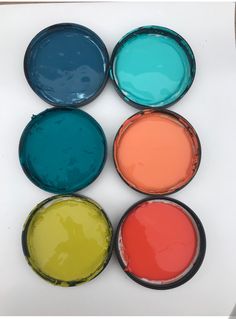 six different colors of paint sitting on top of each other in glass bowls with lids