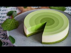 a green and white cheesecake sitting on top of a plate next to some leaves