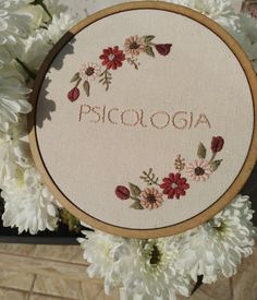 a close up of a embroidery on a wooden hoop with flowers in the background and words piscoa