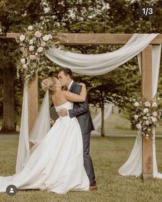 a bride and groom kissing under an arch decorated with flowers