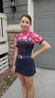 a young woman standing in front of a house wearing a short skirt and red shirt