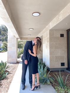 a man and woman kissing in front of a building