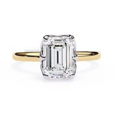 an emerald - cut diamond engagement ring in yellow and white gold, set with a tapered band