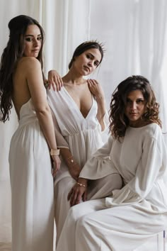 three women in white dresses posing for the camera