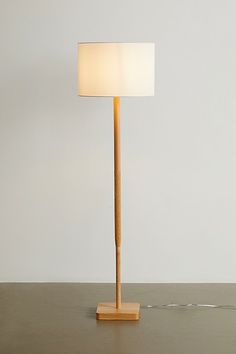 a wooden floor lamp with a white shade