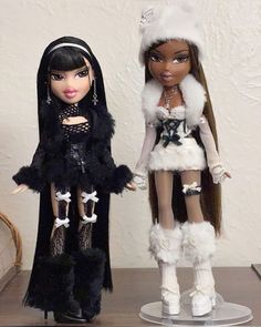 two dolls standing next to each other on a table