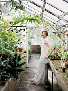 a woman standing in a greenhouse with lots of plants