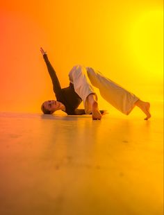 a man and woman doing a handstand on the dance floor in front of an orange background