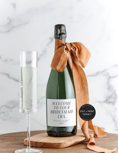 a bottle of champagne next to a glass on a wooden board with a ribbon around it