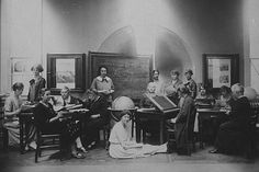 an old black and white photo of people sitting at desks in front of chalkboards