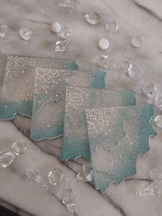 three pieces of glass sitting on top of a marble table covered in crystal beads and confetti