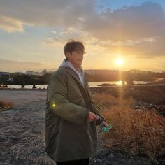 a man standing on top of a dry grass covered field next to a body of water