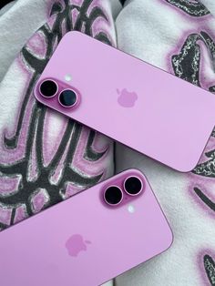 two pink iphones are laying next to each other on a blanket with black and white designs