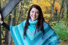 a woman wearing a blue and green crocheted shawl holding up a black umbrella