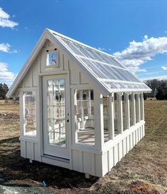 a small white house sitting in the middle of a field