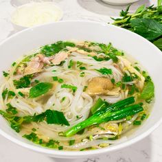 a white bowl filled with noodle and meat soup on top of a marble counter