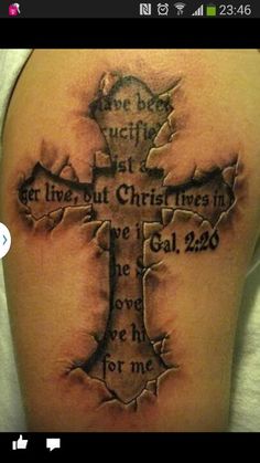 a cross tattoo on the back of a woman's shoulder with words written in it