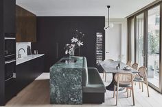 a kitchen with marble counter tops and wooden chairs in front of an open floor plan