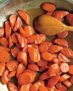 cooked carrots and brown sauce in a pan with a wooden spoon on the side