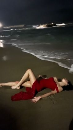 two women in red swimsuits laying on the beach at night with full moon behind them