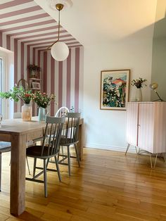 a dining room with striped walls and wooden floors