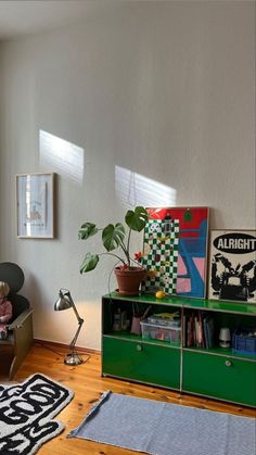 a living room filled with furniture and a green book shelf on top of a hard wood floor