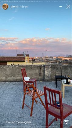 two wooden chairs sitting next to each other on top of a cement floor covered roof