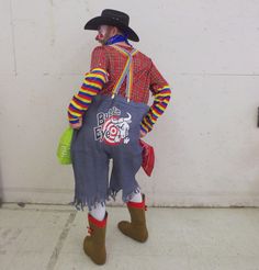 a man dressed as a clown standing in front of a wall with his back to the camera