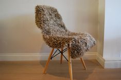 a chair made out of sheepskin sitting on top of a hard wood floor next to a white wall