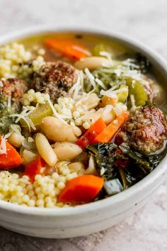 a white bowl filled with meatballs, rice and veggies on top of a table