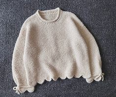 a white sweater sitting on top of a carpet