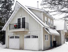 a white house with two garages on the front and second story covered in snow