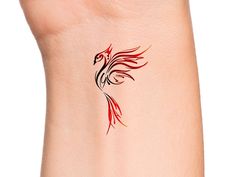 a red and black bird tattoo on the back of a woman's left arm