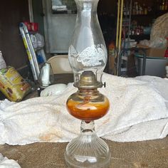 an old fashioned oil lamp sitting on top of a table next to a white towel