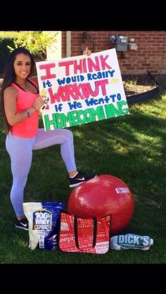 a woman holding a sign in front of some bags and an exercise ball on the grass