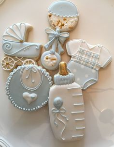 decorated cookies on a white plate with blue trimmings and baby items in the middle