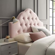 a pink headboard on a bed in a room with grey walls and white pillows