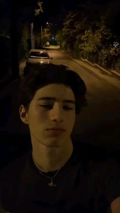 a young man sitting in the middle of a street at night with his eyes closed