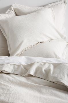 an unmade bed with white sheets and pillows