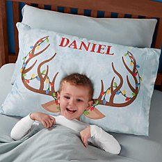 a little boy laying in bed with his name on the pillow and reindeer antlers