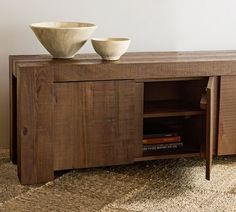 two bowls sit on top of a wooden entertainment center with an open shelf underneath it