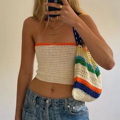 a woman taking a selfie with her cell phone and wearing a crochet top