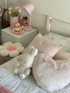 a stuffed animal laying on top of a bed next to pillows